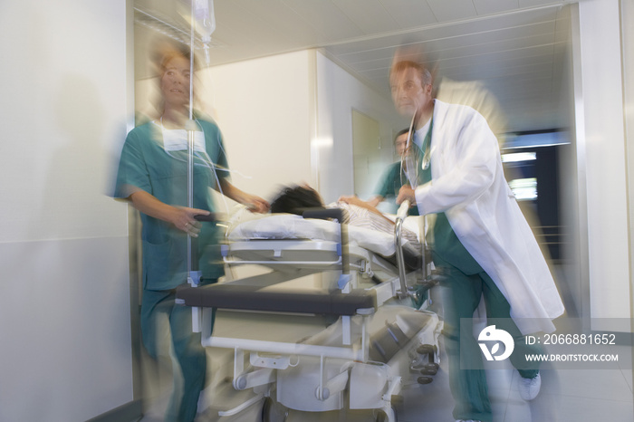 Medical workers moving patient on gurney through hospital corridor