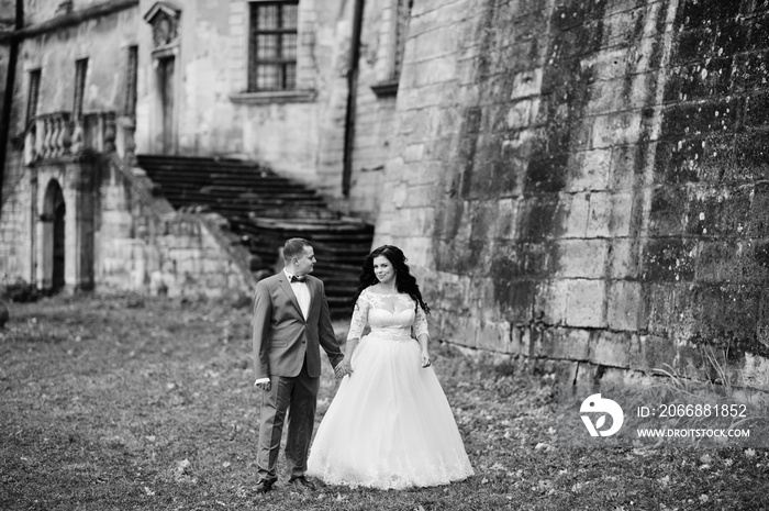 Beautiful wedding couple standing outside with a beautiful architectural background. Black and white photo.