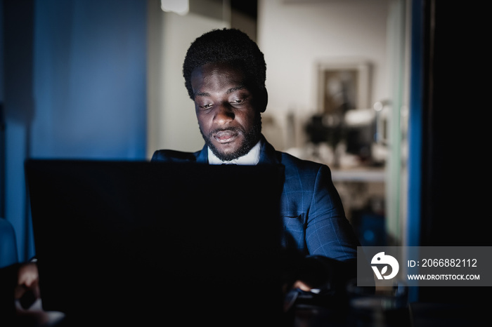 African american man working at night time inside modern office - Focus on face