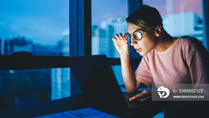 Surprised woman working on laptop in modern workspace