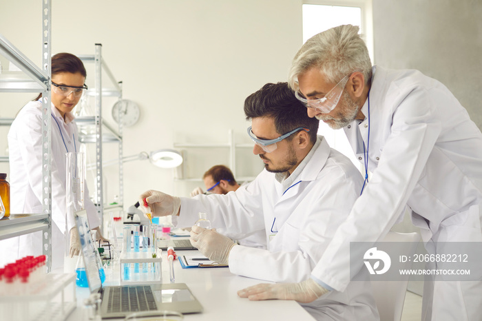 Group of serious interested scientists working in laboratory, doing advanced scientific research and using chemical reactions and modern lab equipment to analyze medical samples