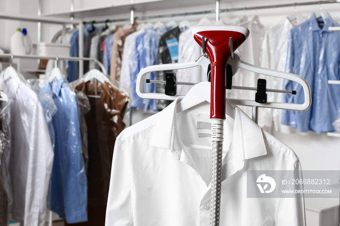 Rack with clothes and steamer in modern dry-cleaner’s