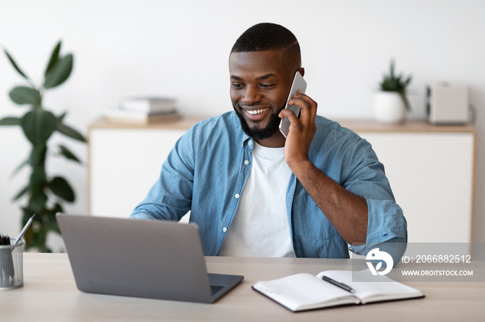 Remote Business. Black Male Freelancer Worjing With Cellphone And Laptop At Home