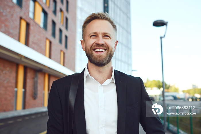 A smiling businessman is standing against the backdrop of a business building