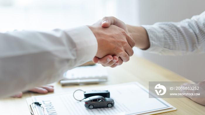 Insurance concept the car broker shaking hand with his customer after finishing dealing the contract