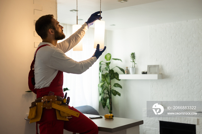 Electrician worker man assembling electric lamps in new apartment.