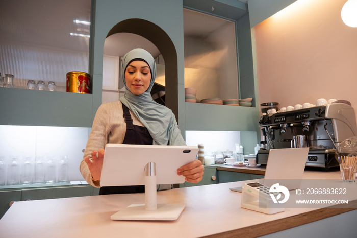 Young woman in hijab working in cafe