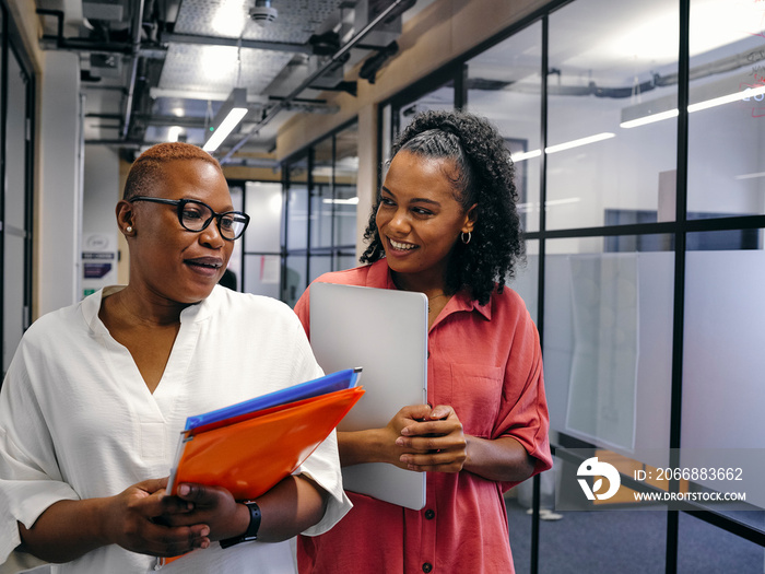 Two women walking in office hallway