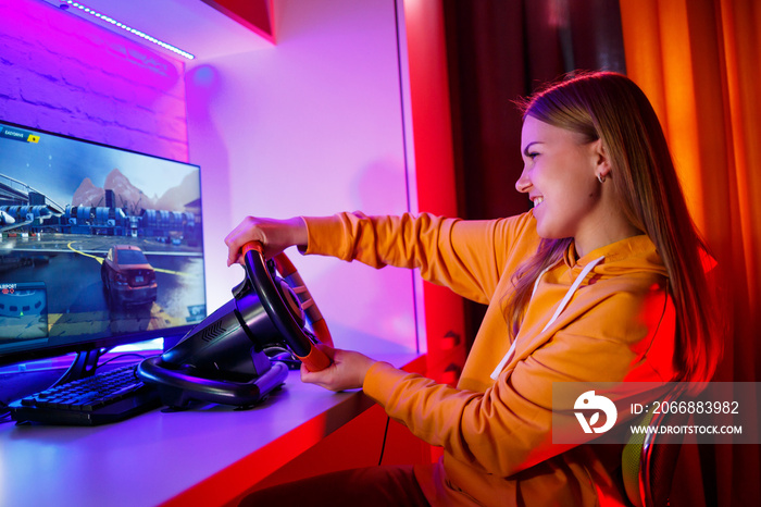 girl gamer playing racing on a computer. She uses a steering wheel. emotional play