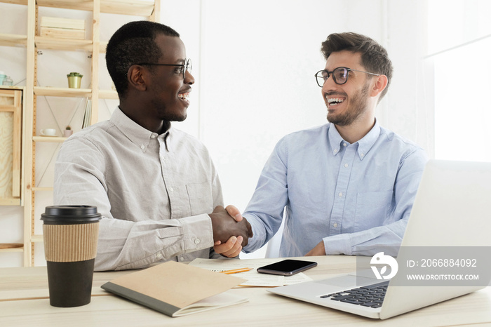 Handshake in office. Young multiethnic men in smart casual wear shaking hands while working together