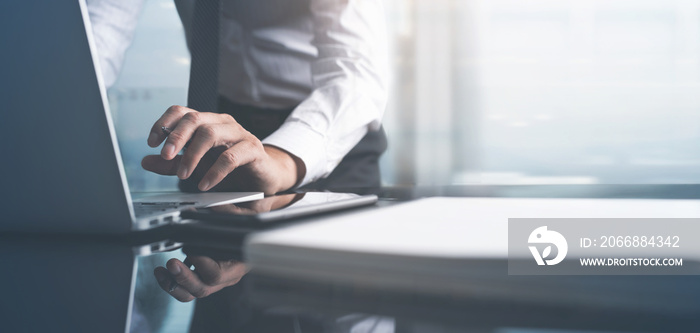 Businessman busy working on laptop computer, surfing the internet with document on table at modern office with blurred copy space