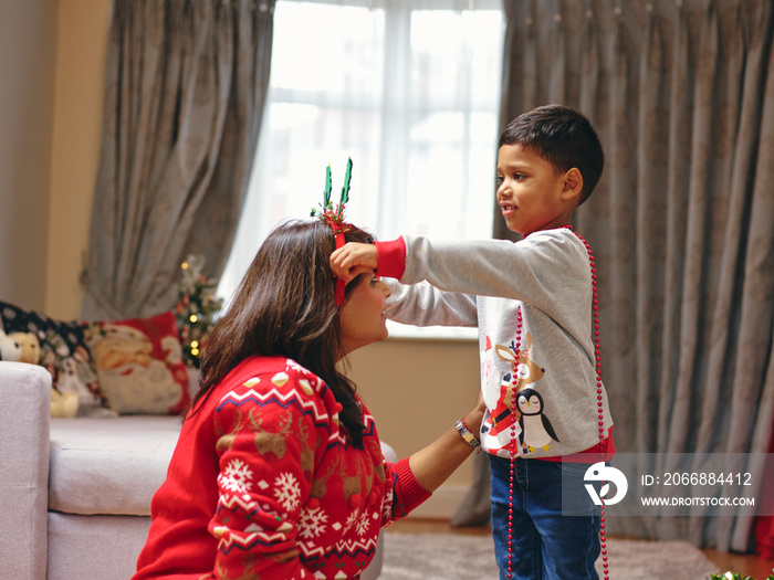 Boy putting Christmas headband on mother