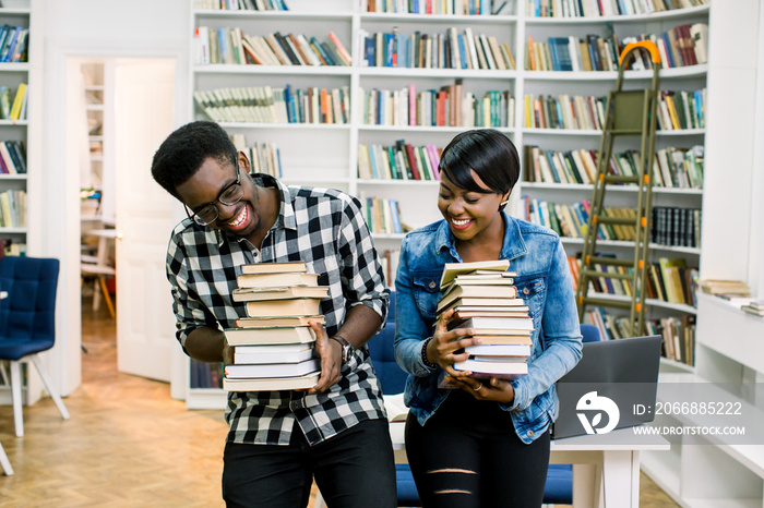 African american students studying together in a library, smiling and holding books