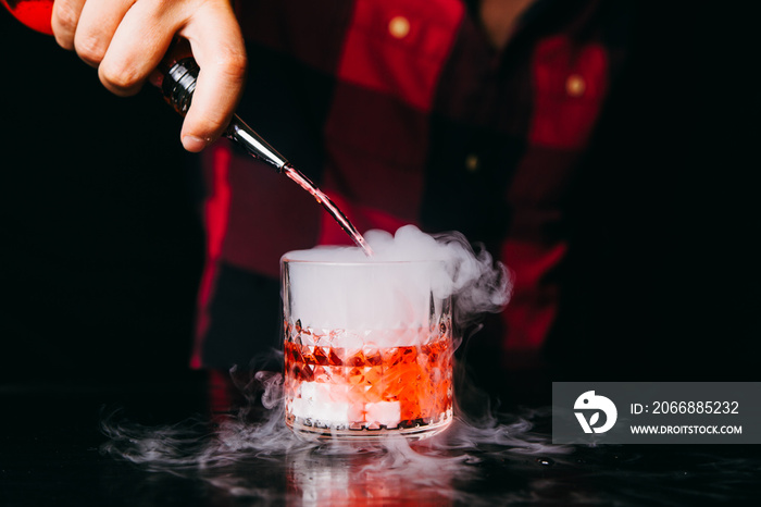 Barman making red smoking cocktail