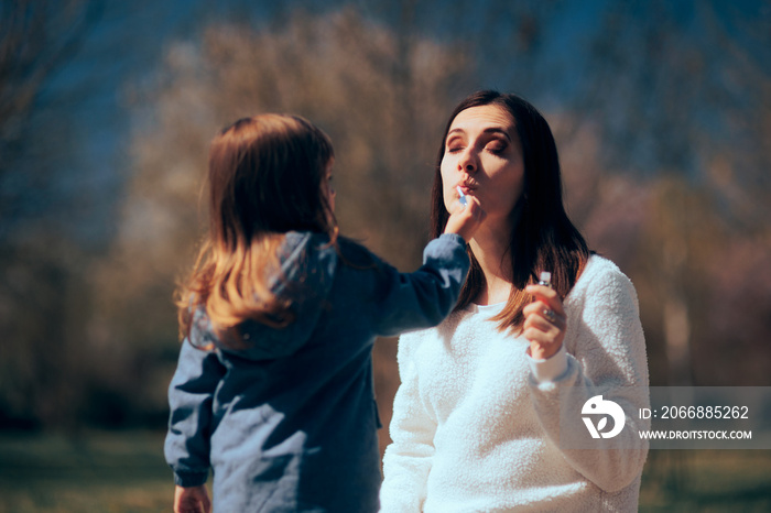 Daughter Helping Mom Applying Lip Gloss Outdoors