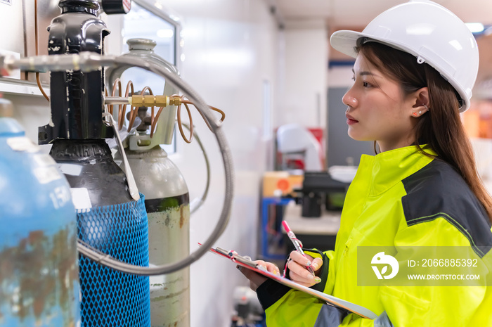 Asian engineer working at Operating hall,Thailand people wear helmet  work,He worked with diligence and patience,she checked the valve regulator at the hydrogen tank.