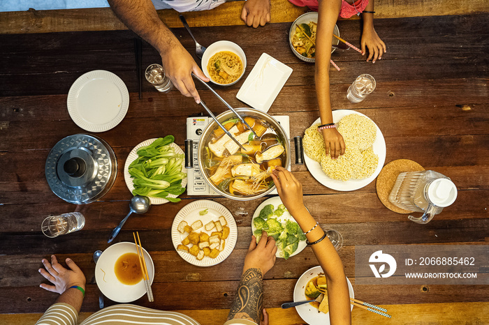 Family dinner eating hotpot together with the parents and kids in the evening