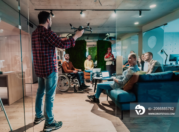 A bearded man in a modern office explaining to his young diverse team how a drone working