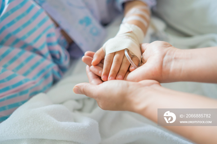 Little girl was sick and her hand was hold by her mother in hospital room. Selective focus,