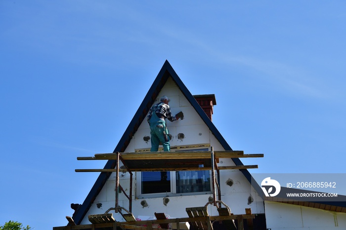 Worker saving heat in the house by insulating the walls with polystyrene