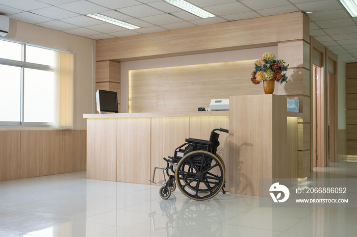 Empty modern wooden reception counter with monitor and wheelchair in the hospital