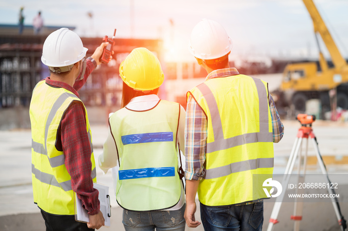 Civil engineers at construction site and a land surveyor using an altometer