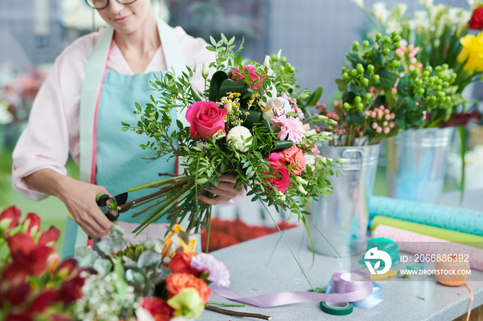 Crop view of smiling woman arranging flower bouquet in shop