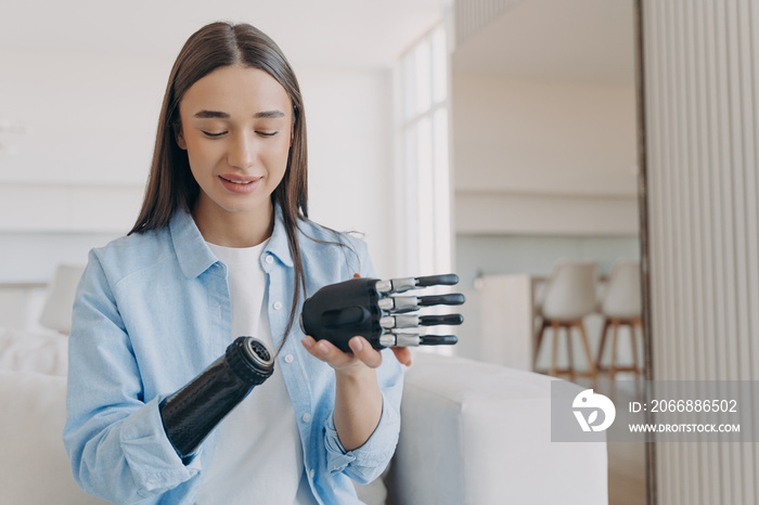 Disabled young woman is assembling bionic arm with hand. Prosthesis is connecting in wrist joint.