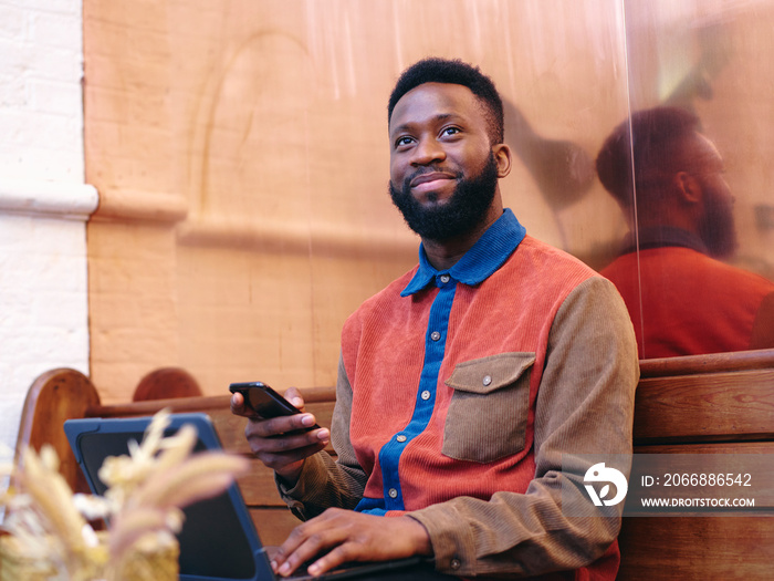 UK, London, Smiling businessman using smart phone and laptop