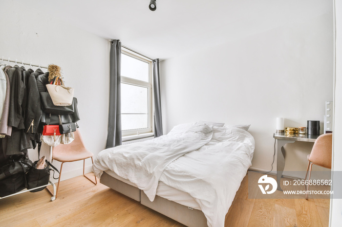 Comfortable armchair and empty shelf placed near bed with soft mattress against white walls with doors in bedroom