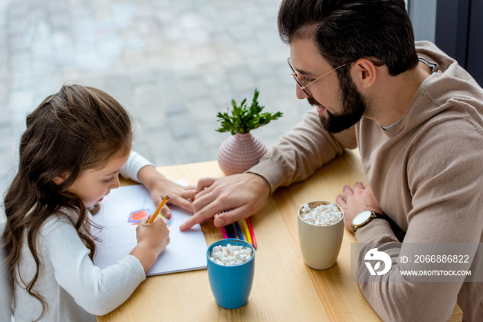 cheerful father showing daughter where to draw