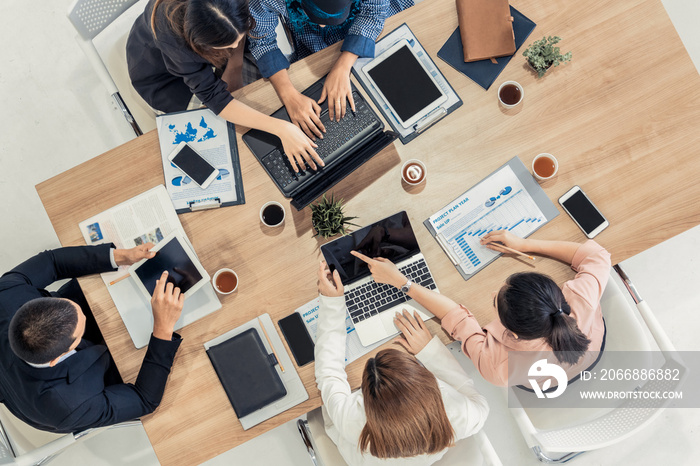 Top view of businessman executive in group meeting with other businessmen and businesswomen in modern office with laptop computer, coffee and document on table. People corporate business team concept.