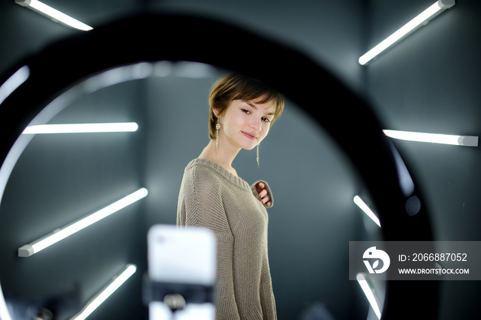 Beautiful teenage girl taking a selfie picture with mobile phone in light of the ring lamp.