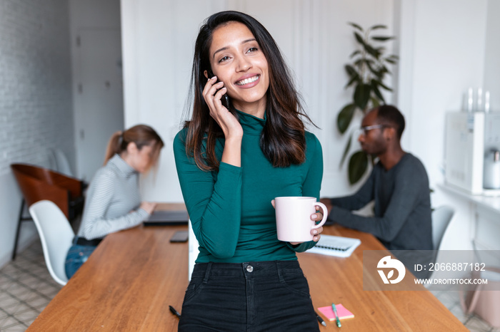 Young indian business woman entrepreneur talking on mobile phone in the office.