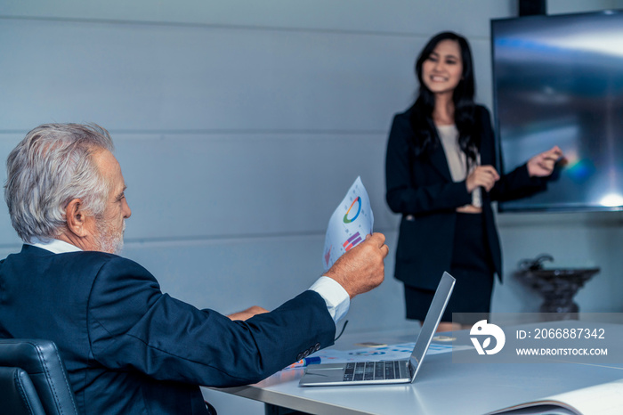 Senior executive manager listening to financial presentation from young businesswoman in meeting room. Secretary presents report to the boss. Business workplace concept.