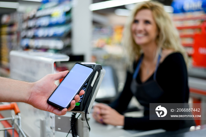 Mans hand making a contactless payment with his smartphone at a supermarket