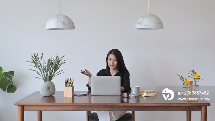 Young business woman having video conference meeting with colleagues, looking at laptop computer screen.