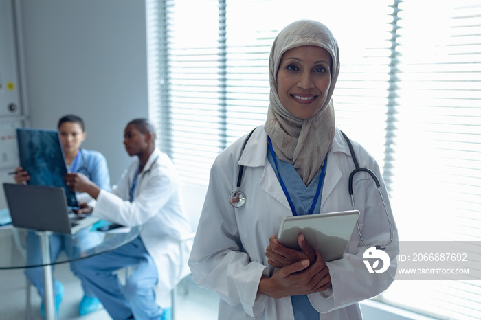 Female doctor in hijab standing with digital tablet in hospital