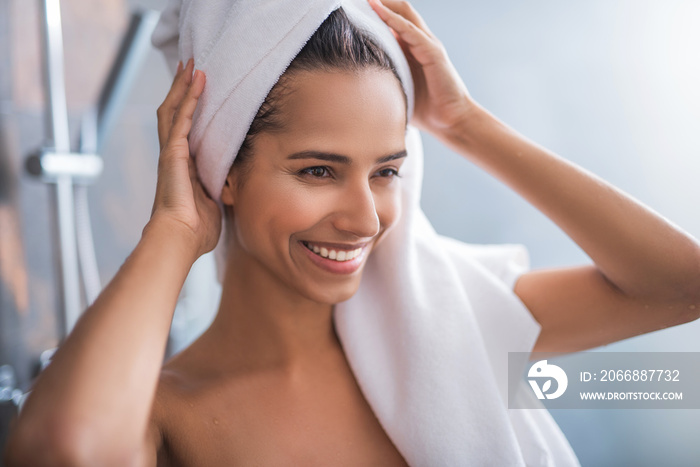 Portrait of beaming lady touching head with arms after taking shower