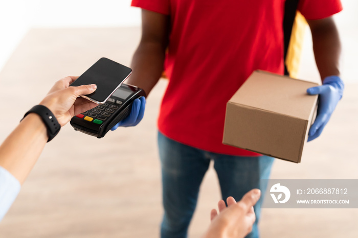 Black man holding POS machine client paying with smart phone