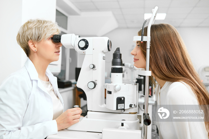 Photo of skilled , expirienced ophthalmologist checking patient’s vision in the laboratory. helping to save and improve eye health and vision. Wearing white uniform, looking professinal.