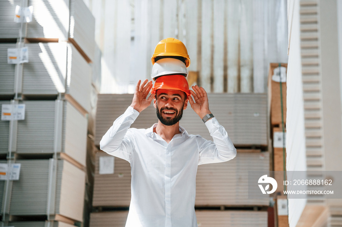 Having fun with hard hats. Storage worker is in the warehouse with bunch of products