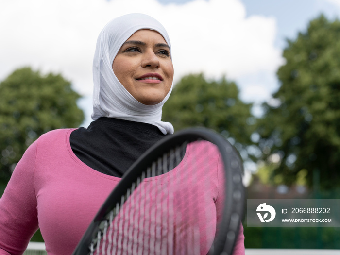 UK,Sutton,Portrait of smiling woman in headscarf at tennis court