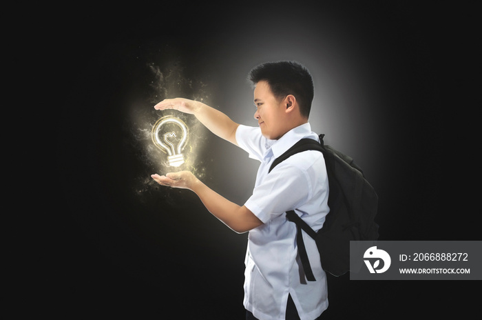 Happy young male student in school uniform with back pack beholding an idea. Light bulb idea concept. Success, creative, and idea concept in gray isolated background. Back to school.