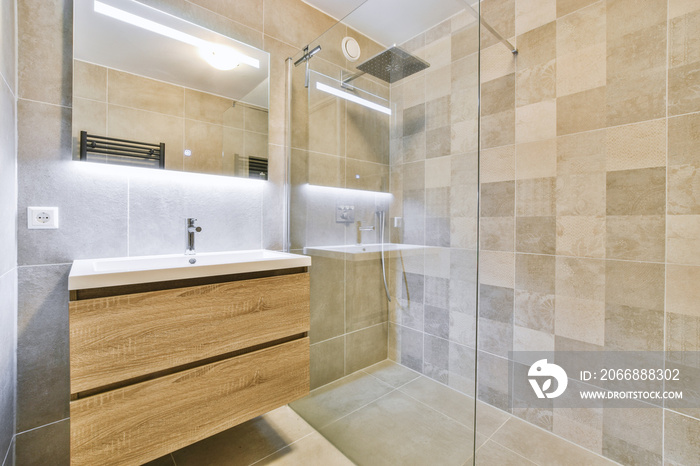 Sinks with mirrors and shower box with glass door in modern bathroom with white tiled walls