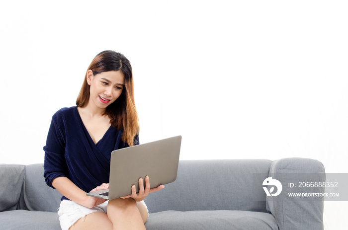 happy beautiful young asian woman using laptop computer on on sofa at home on white background, soft focus, lifestyle smart communication technology, online shopping and payment online concept