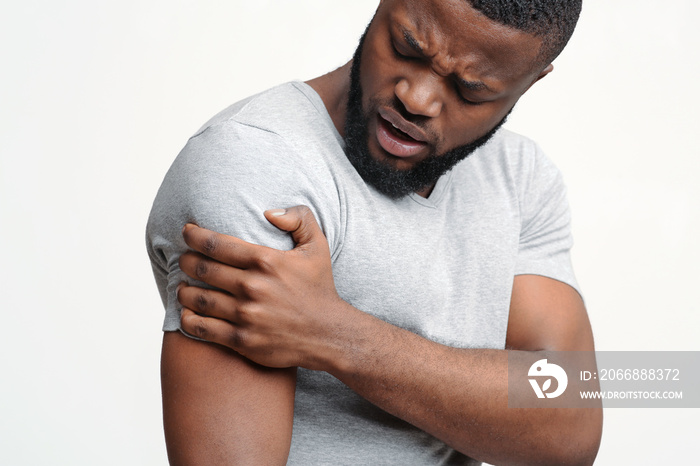 Young guy rubbing his itching forearm over white background