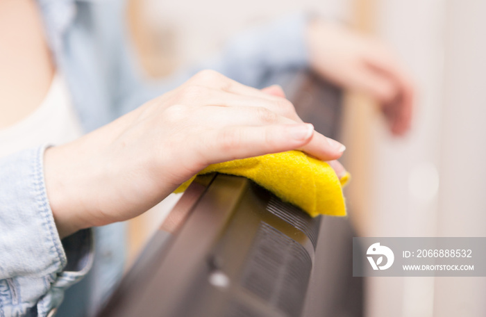 Housewife cleaning the dust of tv in living room.