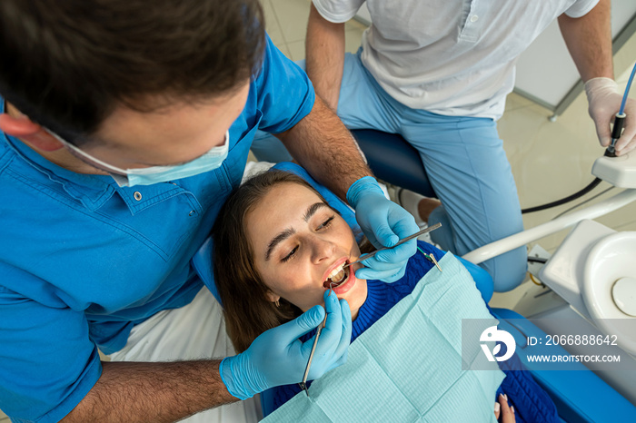 the dentist with the assistant carries out professional brushing of teeth of the patient.