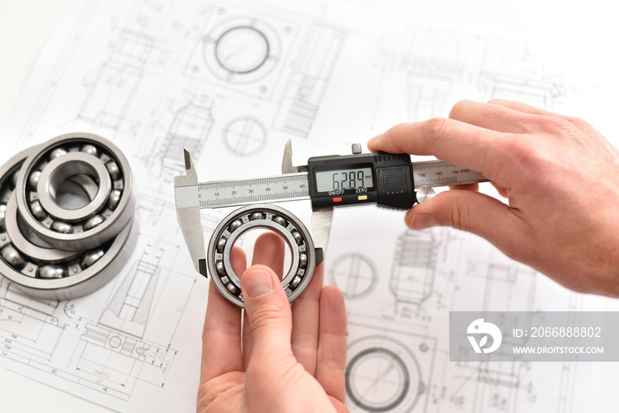 Quality control in modern mechanical engineering - caliper gauges, technical drawing and ball bearings on white background